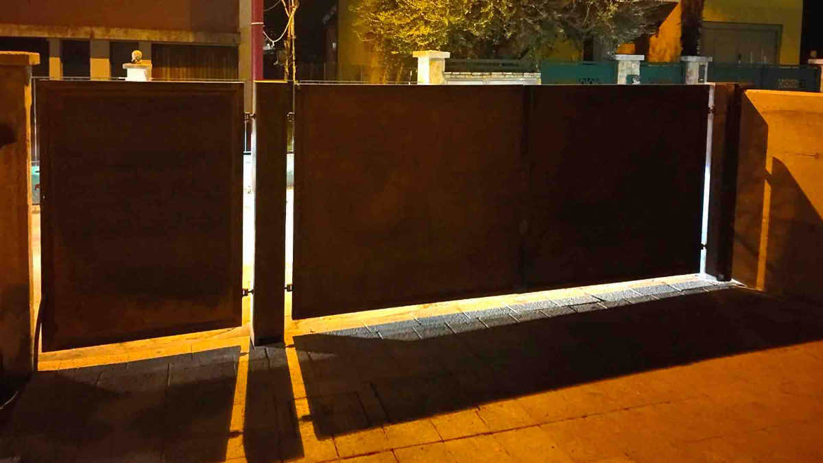Cancello in acciaio corten aperto, vista dal lato interno dell'abitazione